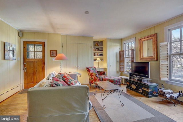 living area featuring a healthy amount of sunlight, a baseboard heating unit, and wood finished floors