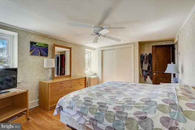 bedroom featuring multiple windows, radiator heating unit, wood finished floors, and crown molding