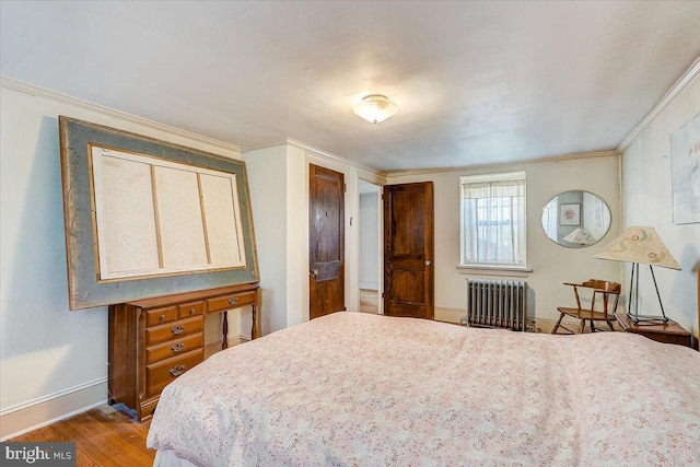 bedroom with baseboards, radiator heating unit, wood finished floors, and crown molding