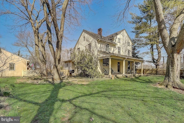 view of front of house featuring a front lawn, a chimney, fence, and stucco siding