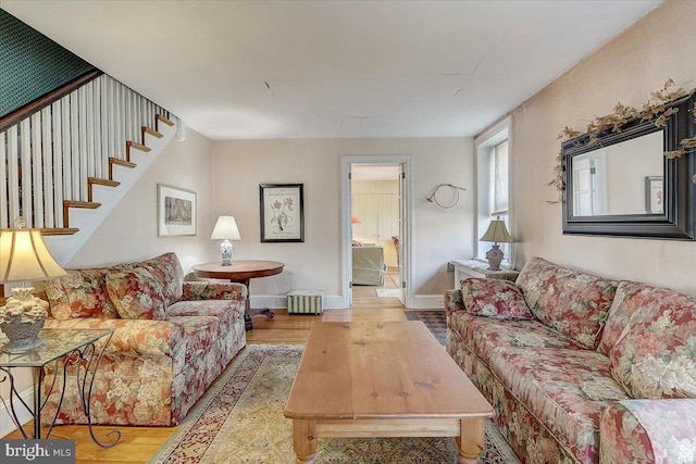 living area featuring stairs, radiator, wood finished floors, and baseboards