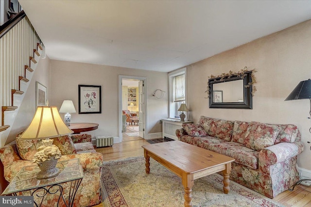 living room with stairs, baseboards, and wood finished floors