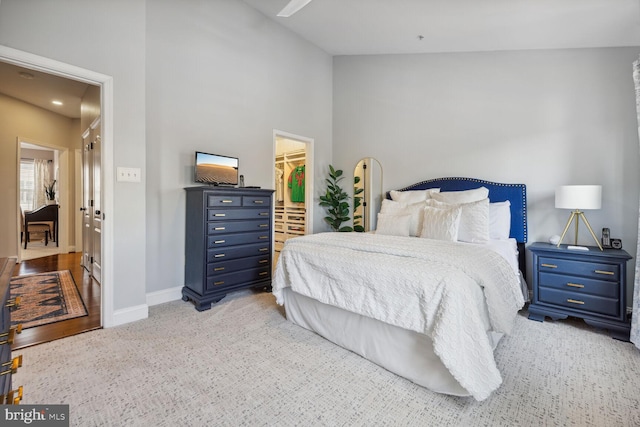 bedroom featuring a closet, carpet, a walk in closet, and baseboards