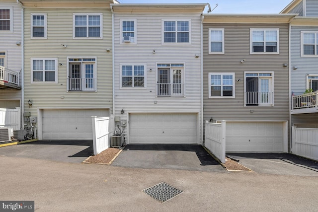 back of house featuring driveway, an attached garage, and central air condition unit