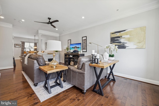 living area featuring dark wood-style floors, baseboards, ornamental molding, and a ceiling fan