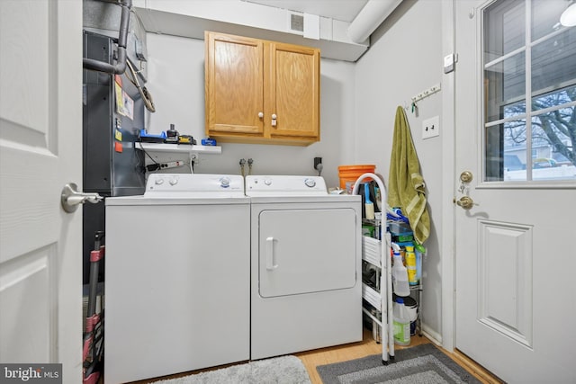 laundry area with cabinet space, washing machine and dryer, visible vents, and wood finished floors