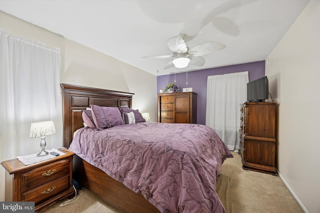 bedroom with a ceiling fan, light carpet, and baseboards