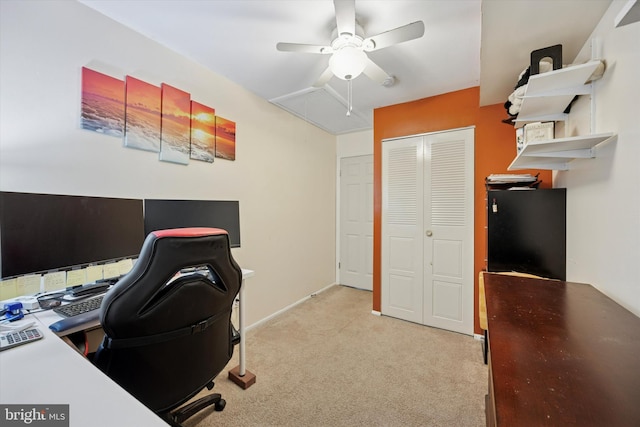 office space featuring light carpet, attic access, and ceiling fan