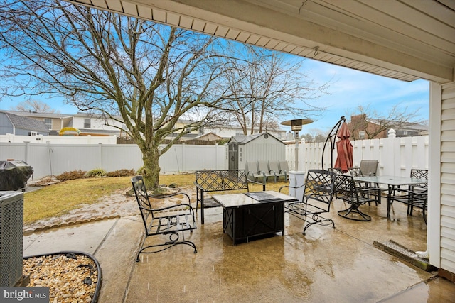 view of patio / terrace featuring a storage shed, a fire pit, a fenced backyard, an outbuilding, and outdoor dining space