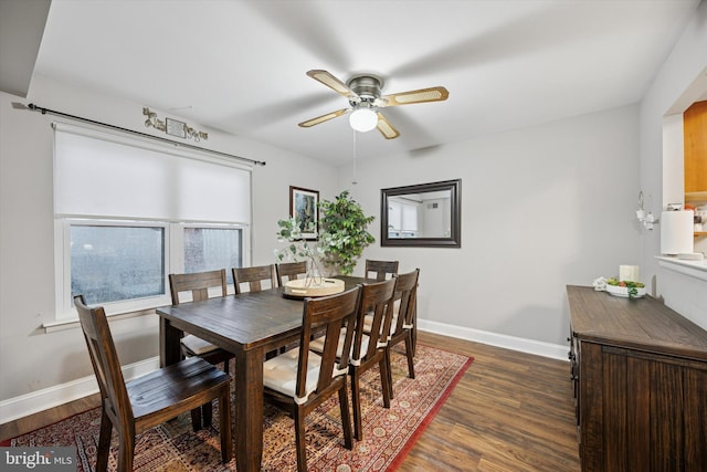 dining area with dark wood finished floors, a ceiling fan, and baseboards