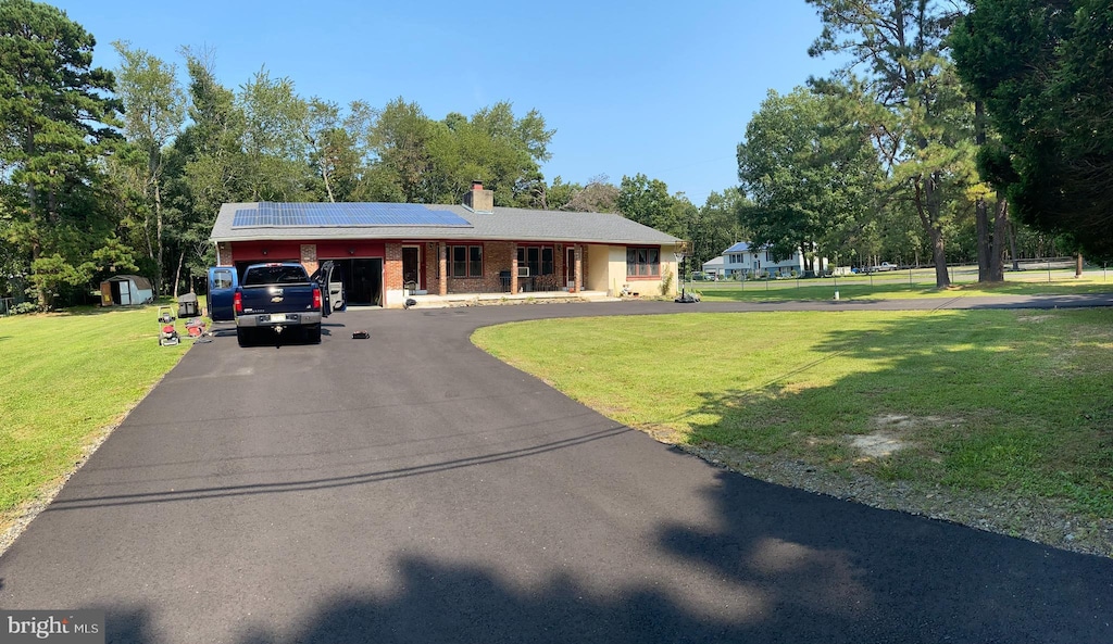 ranch-style home with brick siding, a chimney, aphalt driveway, and a front yard