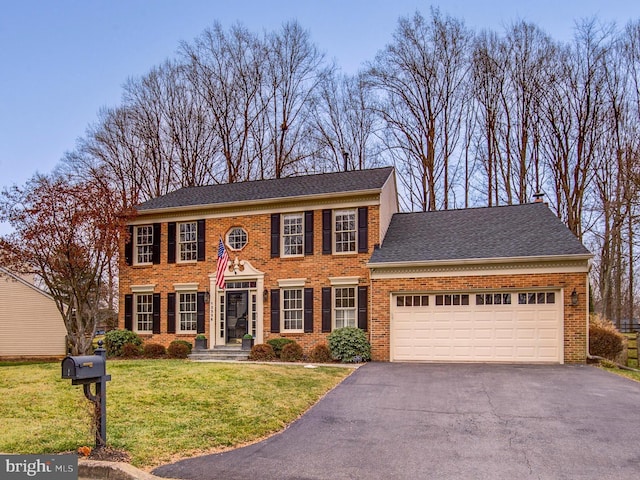 view of front of house with brick siding, a shingled roof, an attached garage, driveway, and a front lawn