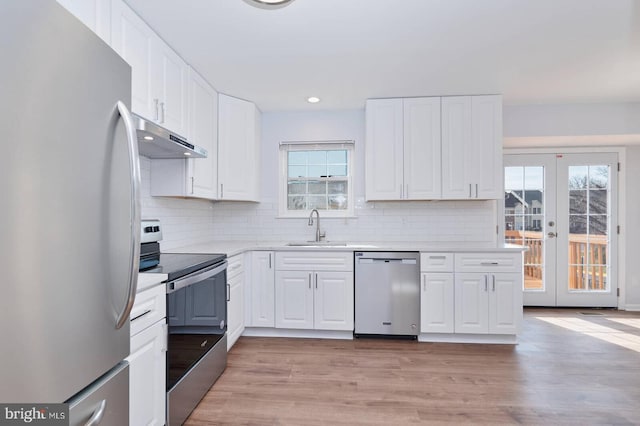 kitchen with under cabinet range hood, light countertops, white cabinets, stainless steel appliances, and a sink