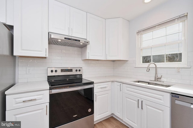 kitchen with white cabinetry, under cabinet range hood, appliances with stainless steel finishes, and a sink