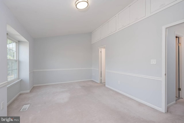 unfurnished room featuring visible vents, light carpet, and baseboards