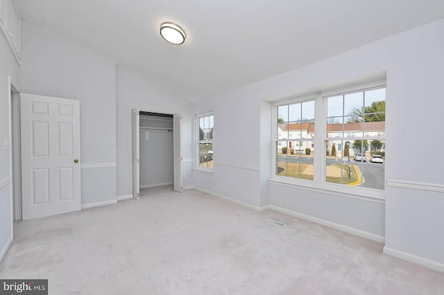 unfurnished bedroom with carpet, visible vents, baseboards, vaulted ceiling, and a closet