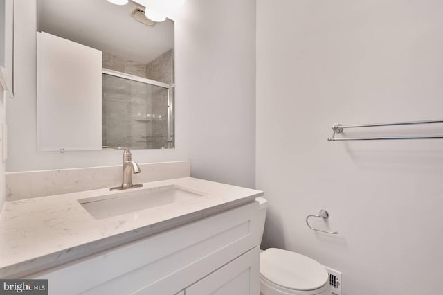 full bathroom with vanity, a shower stall, toilet, and visible vents