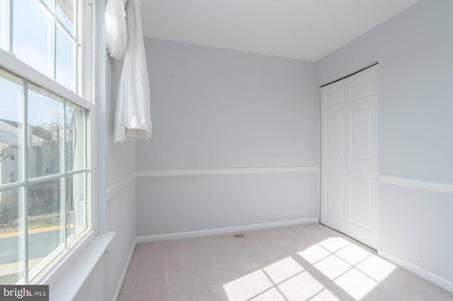 unfurnished bedroom featuring a closet, baseboards, and light colored carpet