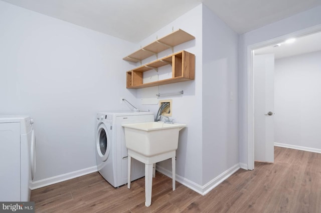 washroom with baseboards, wood finished floors, laundry area, and washing machine and clothes dryer