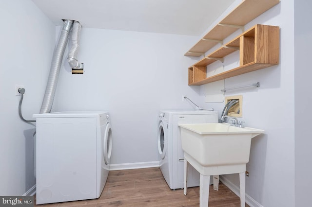 laundry room with baseboards, laundry area, light wood-style flooring, washer and dryer, and a sink