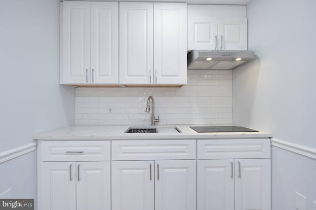 kitchen featuring a sink, decorative backsplash, under cabinet range hood, white cabinetry, and black electric cooktop