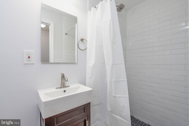 full bathroom featuring tiled shower and vanity