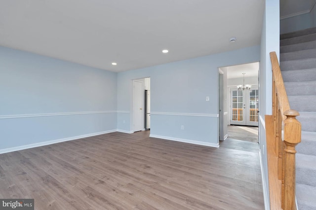 spare room with stairway, baseboards, and wood finished floors