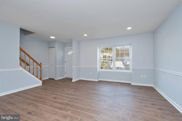 empty room with recessed lighting, stairway, baseboards, and wood finished floors