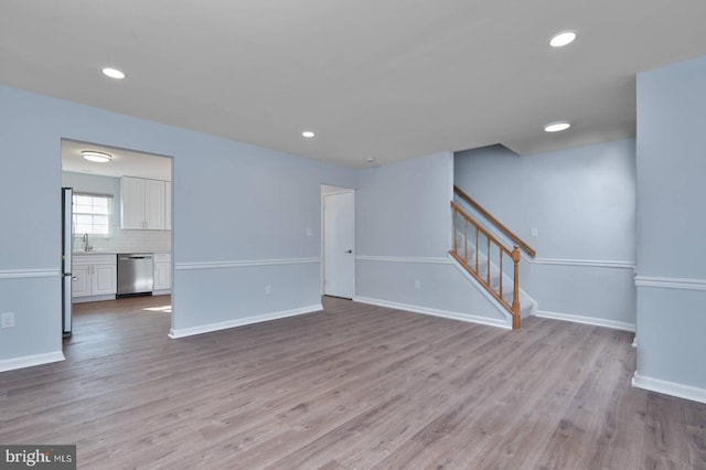 unfurnished living room with recessed lighting, stairs, baseboards, and wood finished floors