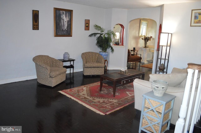 living room featuring arched walkways, baseboards, and wood finished floors