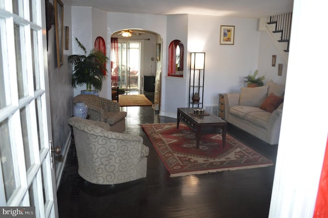 living area with arched walkways, stairway, and wood finished floors