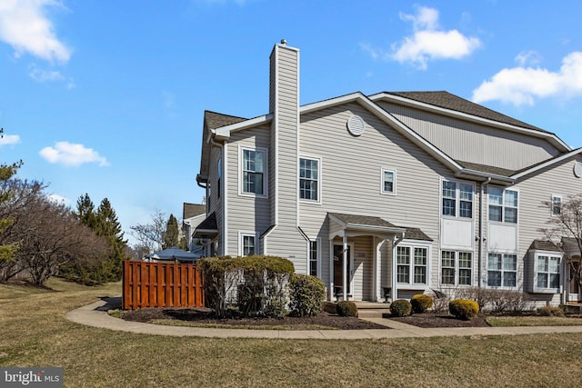 view of front facade with a front yard, fence, and a chimney