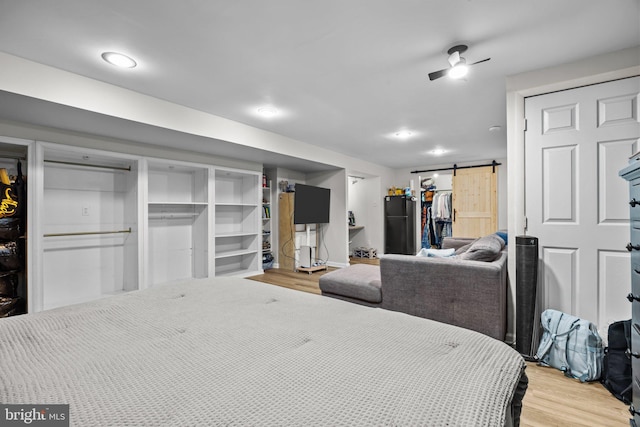 bedroom with a closet, a walk in closet, wood finished floors, and a barn door