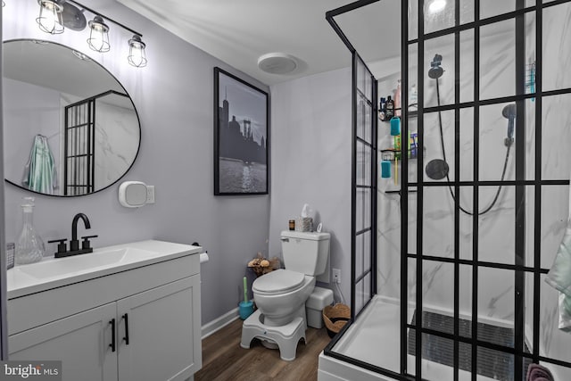 bathroom with wood finished floors, vanity, toilet, and walk in shower