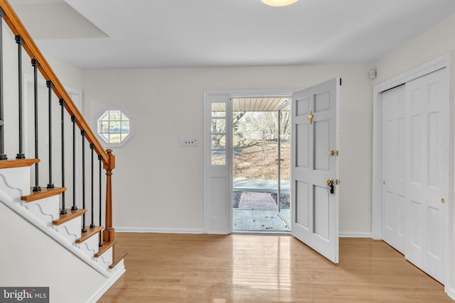 entryway featuring stairway, light wood-type flooring, a wealth of natural light, and baseboards