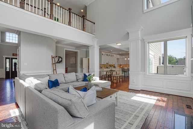 856 N Harrison St, Arlington, VA 22205 - living room featuring wood-type flooring, crown molding, decorative columns, a towering ceiling, and a decorative wall