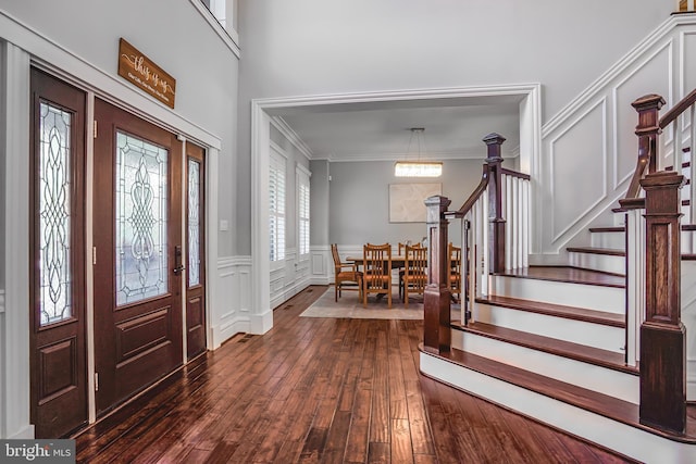 856 N Harrison St, Arlington, VA 22205 - foyer featuring crown molding, dark wood-style flooring, wainscoting, a decorative wall, and stairway