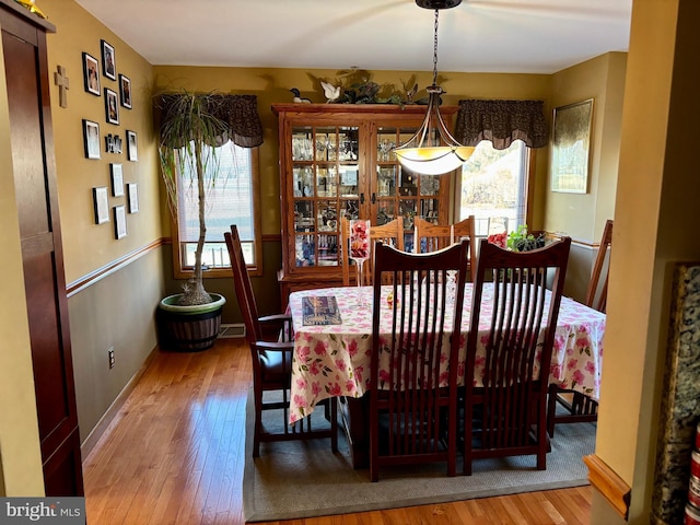 dining space featuring wood-type flooring, visible vents, and baseboards