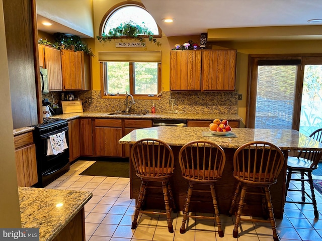 kitchen with brown cabinetry, gas stove, a sink, and decorative backsplash