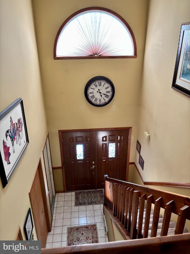 foyer entrance with light tile patterned floors, a high ceiling, and stairway