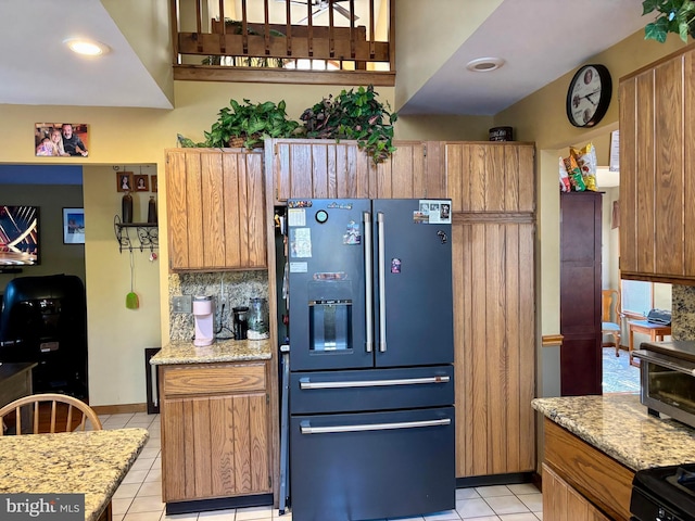 kitchen featuring light tile patterned flooring, a toaster, refrigerator with ice dispenser, tasteful backsplash, and brown cabinetry