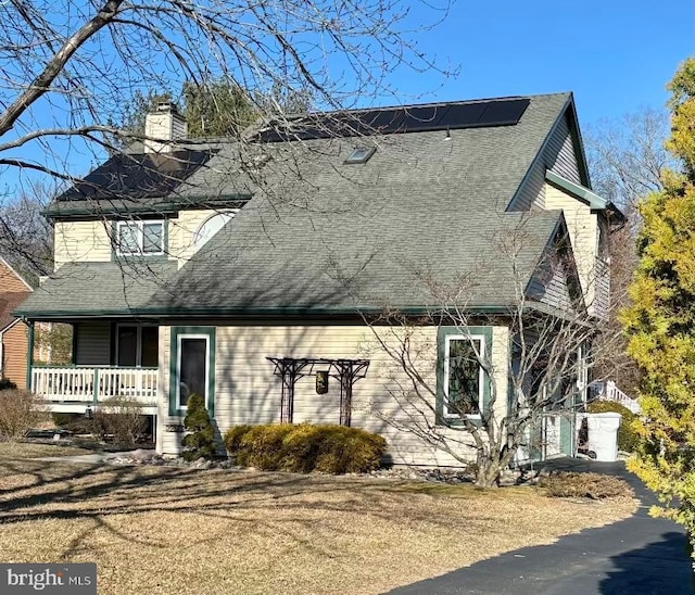 view of front facade with a porch, a shingled roof, and a chimney