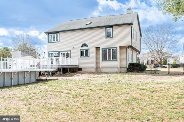 back of house with a chimney, fence, a deck, and a yard