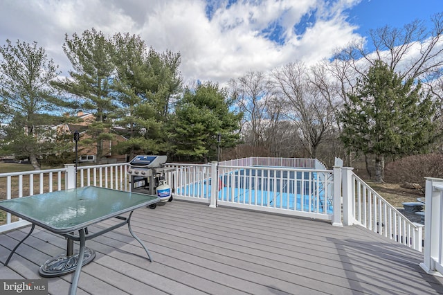 wooden terrace with outdoor dining area, fence, an outdoor pool, and area for grilling