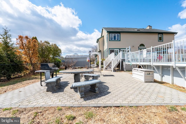 view of patio with a grill, fence, stairway, and a wooden deck