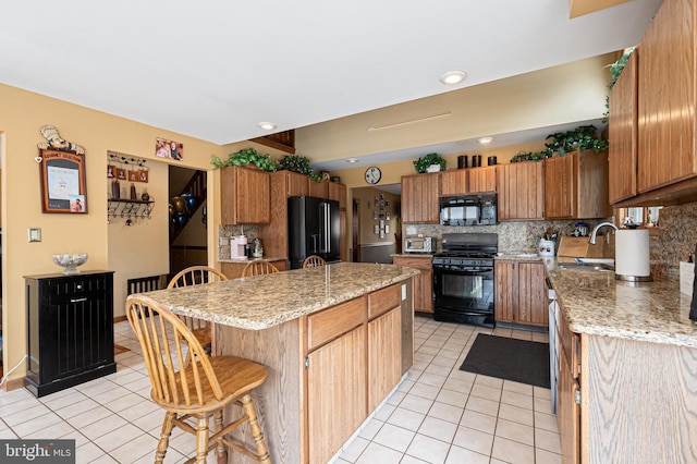 kitchen with light tile patterned flooring, a breakfast bar, a center island, black appliances, and tasteful backsplash