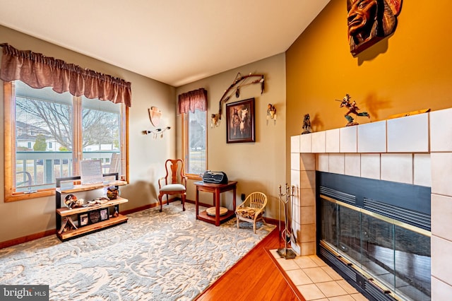 living area with baseboards, wood finished floors, and a tile fireplace