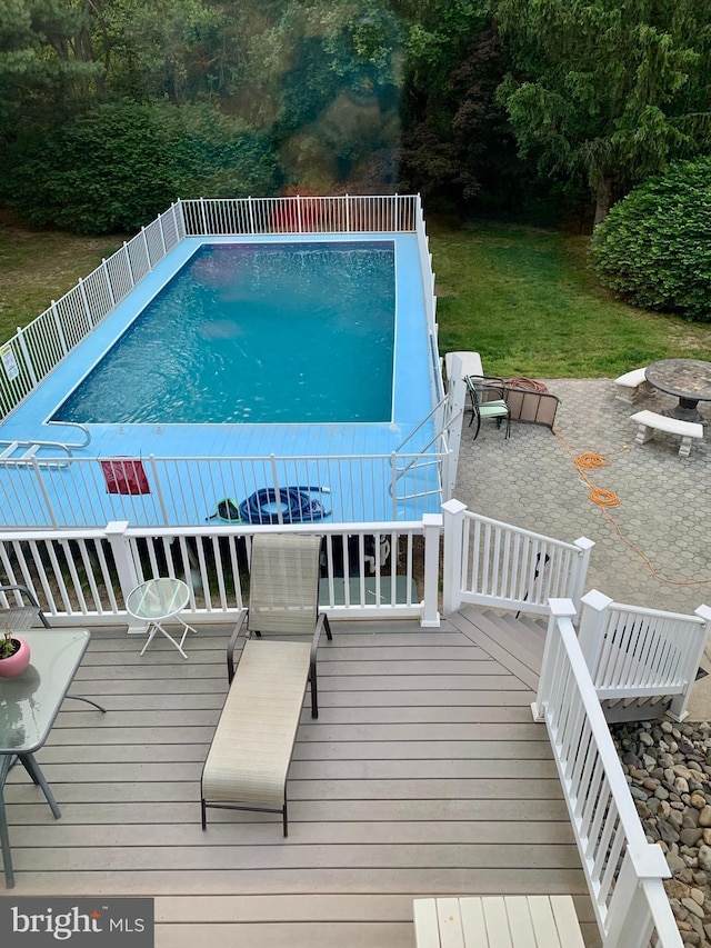 outdoor pool with a lawn and a wooden deck