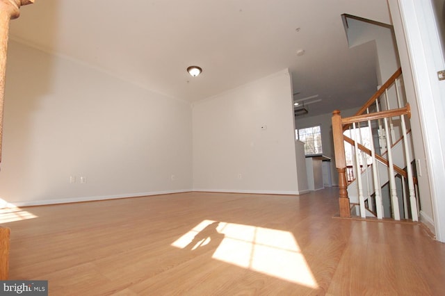 unfurnished room with stairs, baseboards, and wood finished floors