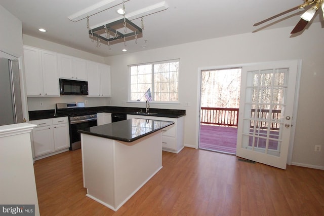 kitchen featuring black appliances, a sink, light wood-style flooring, and white cabinets